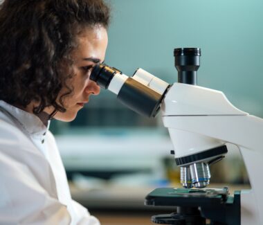 Female researcher looking through microscope at sample