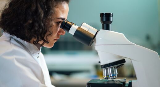 Female researcher looking through microscope at sample