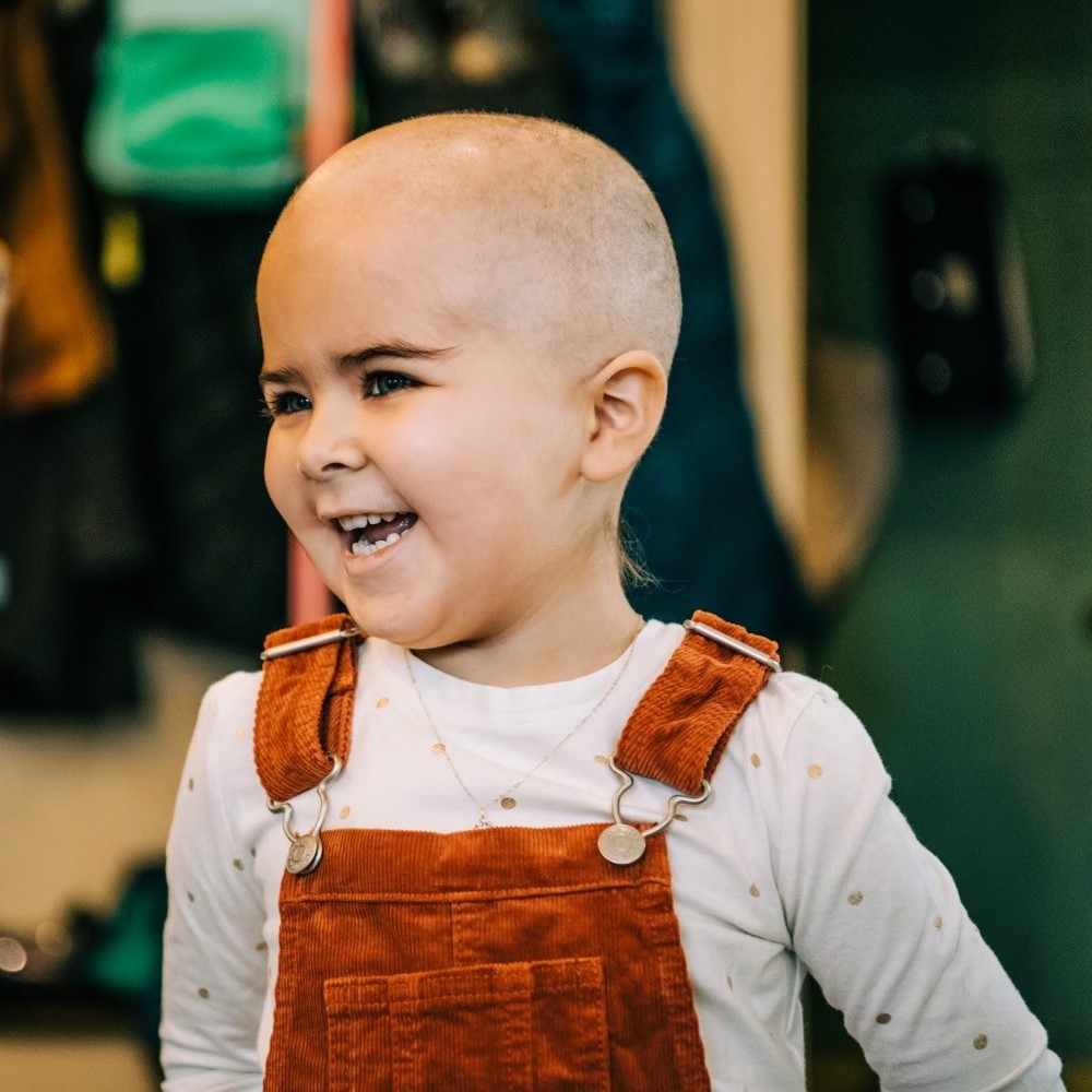 Image of smiling baby Rae in overalls. 