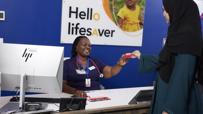Blood donor handing in blood donation card to RIBC staff member