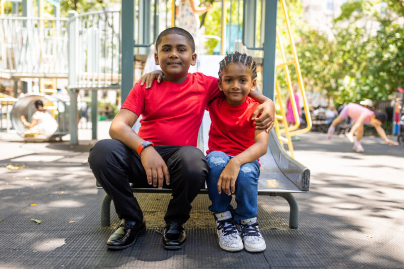 Brothers King and Messiah Singh sitting on a sliding board at a park. The two were born with a rare blood desire known as G6PD and must receive regular blood transfusions.